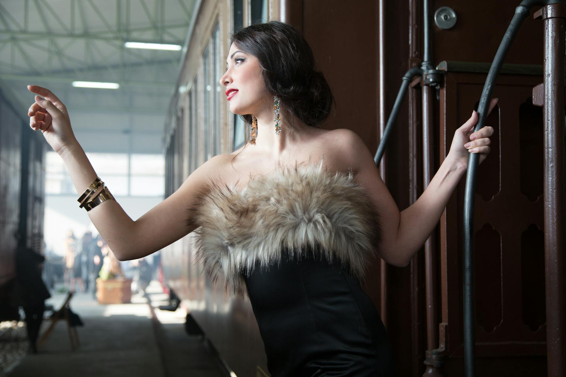 A fashionable woman in fur-trimmed attire poses elegantly on a vintage train.